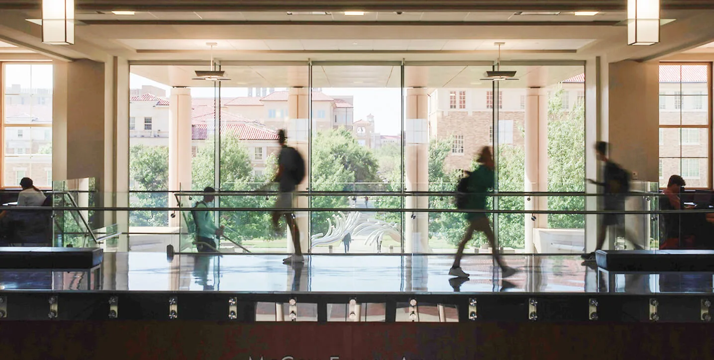 Students walking through a glass-walled campus atrium